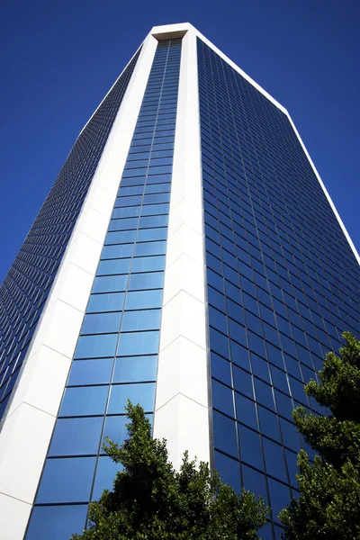 Una torre di vetro incombente riflette il blu cielo — Foto Stock