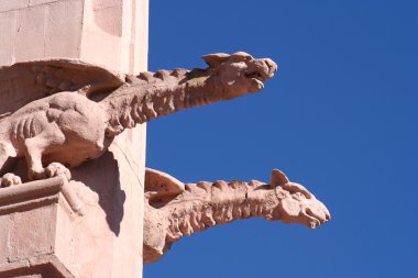 A pair of masonry gargoyles, or chimeras, the right one placid, the left sn clipart