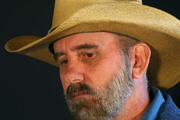 En skäggig cowboy med ett sorgligt, fundersam uttryck — Stockfoto