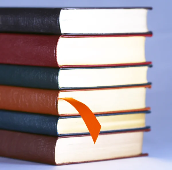Un segnalibro arancione e sei libri legati in pelle — Foto Stock