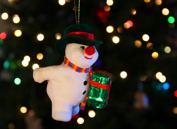 A Frosty the Snowman ornament hangs against a background of shimmering Chri — Stock Photo, Image