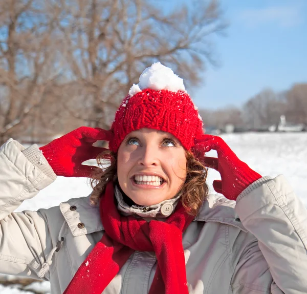 Beautiful woman has a snowball on a red cap — Stock Photo, Image
