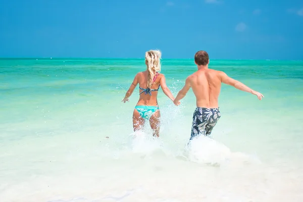 A young couple walking through the waves — Stock Photo, Image