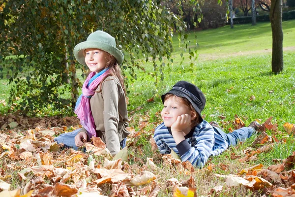 Счастливые девочка и мальчик наслаждаются золотым осенним сезоном — стоковое фото
