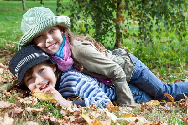 Gelukkig meisje en jongen genieten van gouden herfst vallen seizoen — Stockfoto