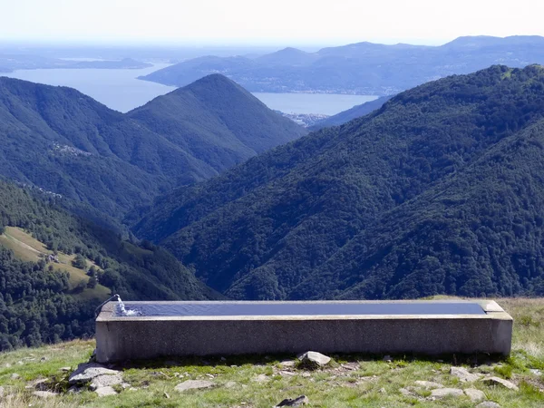 Water trough on lake and mountains background — Stock Photo, Image