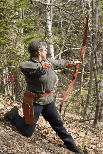Mulher sênior atirando com um arco tradicional — Fotografia de Stock