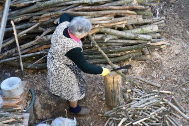 Senior woman cutting wood clipart