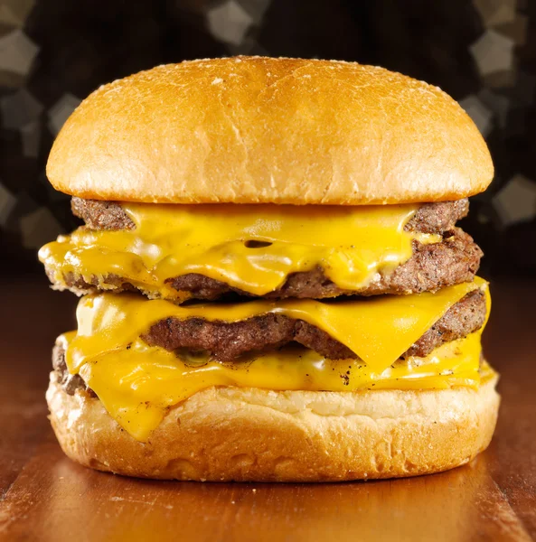 Big cheeseburger with melted cheese and glittery background. — Stock Photo, Image