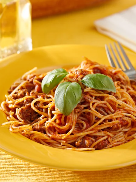 Spaghetti with basil garnish in meat sauce — Stock Photo, Image