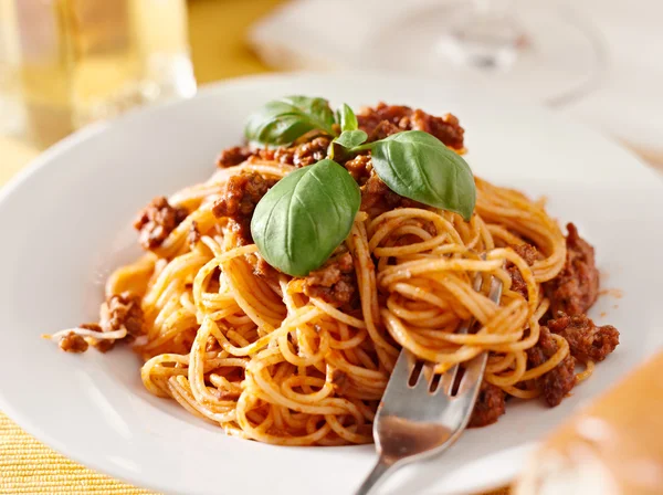 Spaghetti with basil garnish in meat sauce — Stock Photo, Image