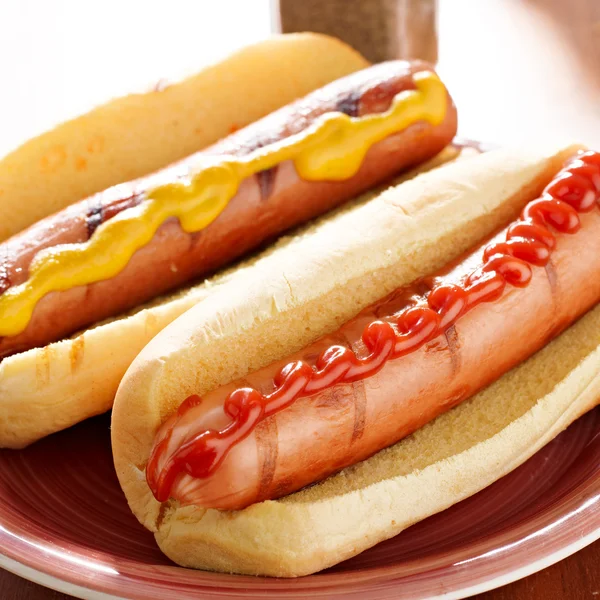 Dois cachorros-quentes em um prato com ketchup e mostarda . — Fotografia de Stock