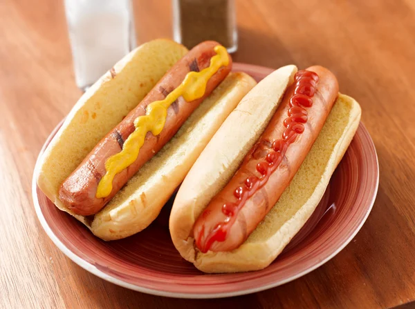 stock image Two hotdogs on a plate with ketchup and mustard.