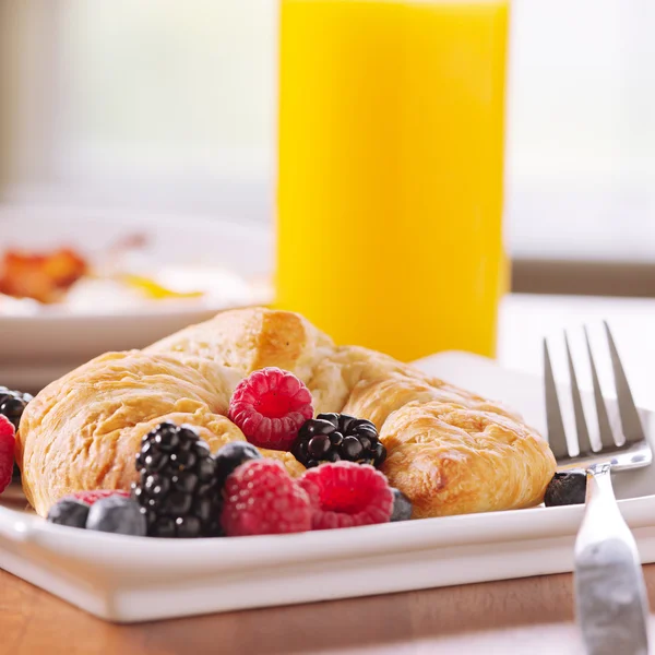 Πρωινό: κρουασάν σερβίρεται με μούρα και ποτήρι χυμό πορτοκαλιού — Φωτογραφία Αρχείου