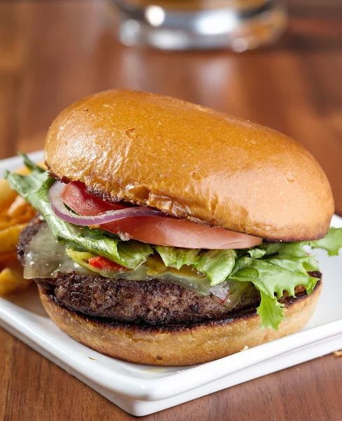 Gurmánské cheeseburger s džbánek piva v pozadí — Stock fotografie