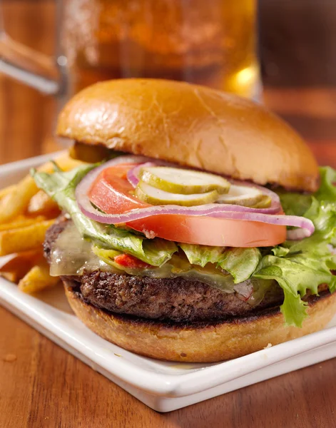 Ínyenc sajtburger és bögre sört háttér — Stock Fotó