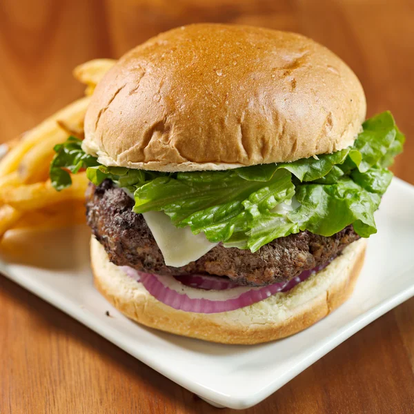 Hamburger mit Käse, Salat, Zwiebeln mit Pommes. Selektiver Fokus auf Burger — Stockfoto