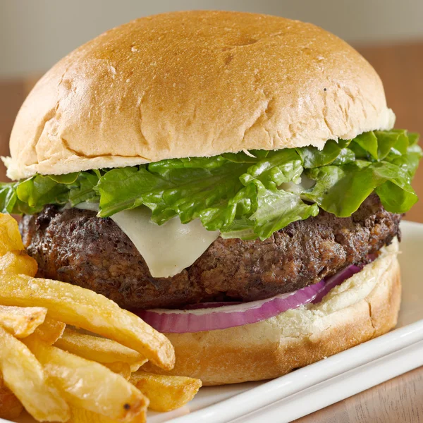 Hamburger mit Käse, Salat, Zwiebeln mit Pommes. Selektiver Fokus auf Burger — Stockfoto