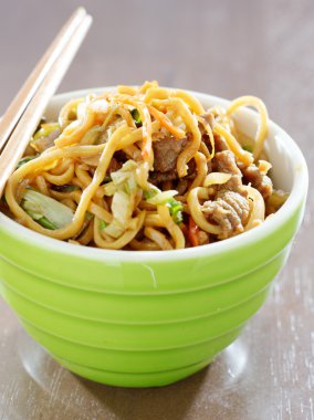 Beef lo mein in a bowl with chopsticks clipart