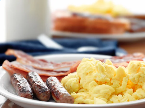 Breakfast meal with sausage and scrambled eggs with bacon. — Stock Photo, Image