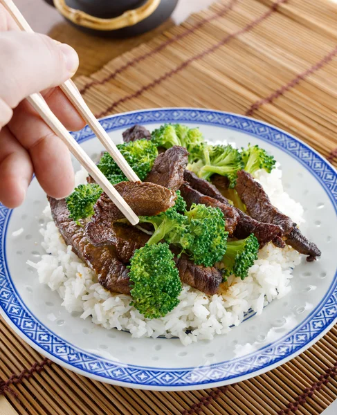 Äta kinesisk biff och broccoli med pinnar — Stockfoto