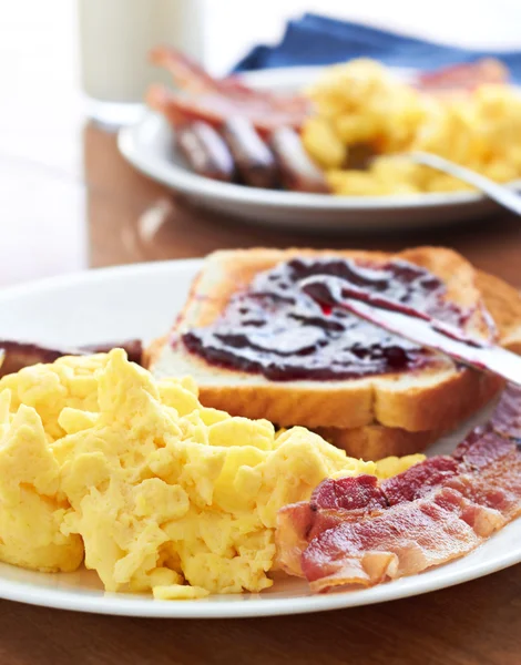 Ontbijt met roerei en spek met toast met jam. — Stockfoto