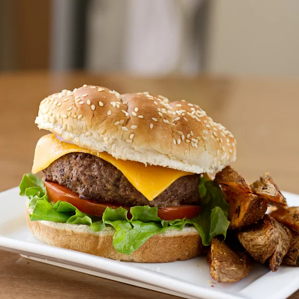 Cheeseburger com cunhas de batata — Fotografia de Stock