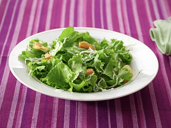 A leafy green salad on a purple table cloth