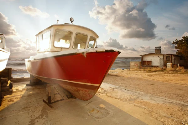 stock image The boat in the parking lot on the background of a beautiful sunset over th