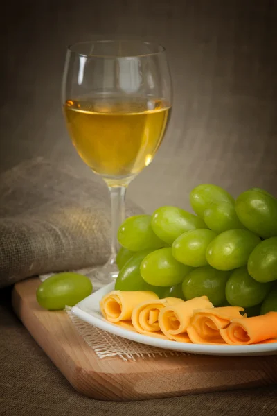 Un bicchiere di vino bianco, uva verde di vino su una superficie di legno — Foto Stock