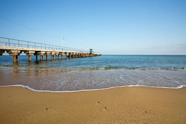 Piaszczysta plaża z molo — Zdjęcie stockowe