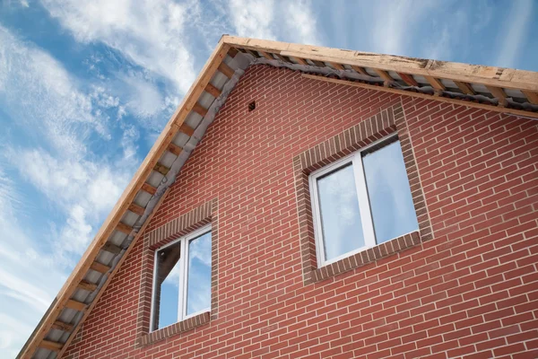 Detalhe da fachada de uma casa de tijolos com um telhado e janelas — Fotografia de Stock