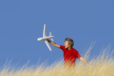 Young Boy Playing with Toy Glider Airplane in Field clipart