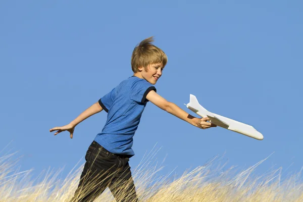 Ung pojke leker med leksak Glider flygplan i fält — Stockfoto