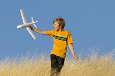 Young Boy Playing with Toy Glider Airplane in Field clipart