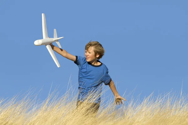 Junge spielt mit Spielzeug-Segelflugzeug auf Feld Stockbild