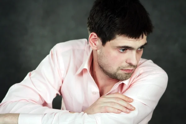 Nachdenklicher junger Mann im rosa Hemd Stockbild