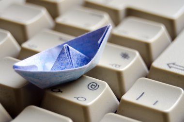 Blue origami boat on keyboard clipart