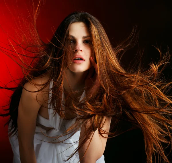 Gyönyörű nő, hosszú, áramló haj, vörös alapon — Stock Fotó