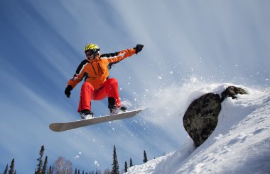 Snowboarder jumping through air with blue sky in background clipart