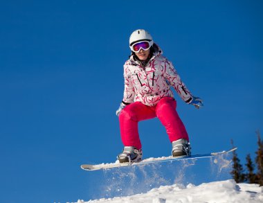 Snowboarder jumping through air with deep blue sky in background clipart