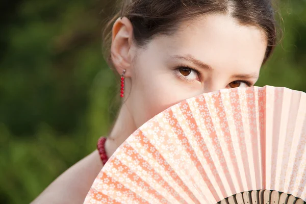 Brunette with a fan in sunset time — Stock Photo, Image