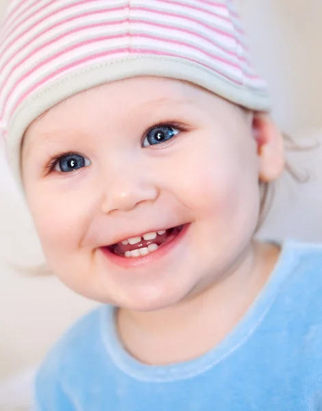 Sorrindo bebê menina mostrando dentes usando um chapéu com flor isolada no branco — Fotografia de Stock