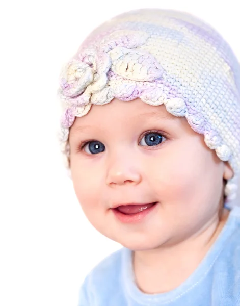 Glimlachende baby meisje weergegeven: tanden dragen van een hoed met bloem geïsoleerd op wit — Stockfoto