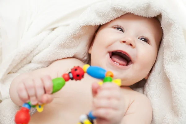 Um lindo bebê sorridente envolto em colcha — Fotografia de Stock