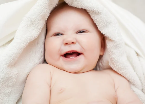 Een mooie glimlachende baby verpakt in quilt — Stockfoto