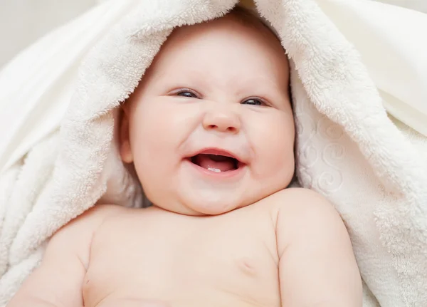 Прекрасный улыбающийся ребенок, завернутый в одеяло — стоковое фото