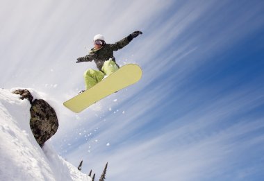 Snowboarder jumping through air with deep blue sky in background clipart