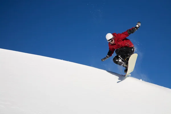 Snowboarder springt durch die Luft mit tiefblauem Himmel im Hintergrund — Stockfoto