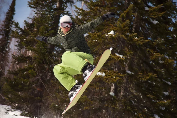 Snowboarder springen door lucht bos op achtergrond — Stockfoto